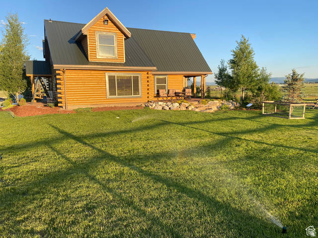 79 Auburn Forest Road Auburn, WY 83111 - Photo 7 of 76 Back of house with log siding, a metal roof, a patio, and a lawn