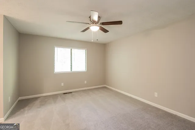 an empty room with a window and a fan