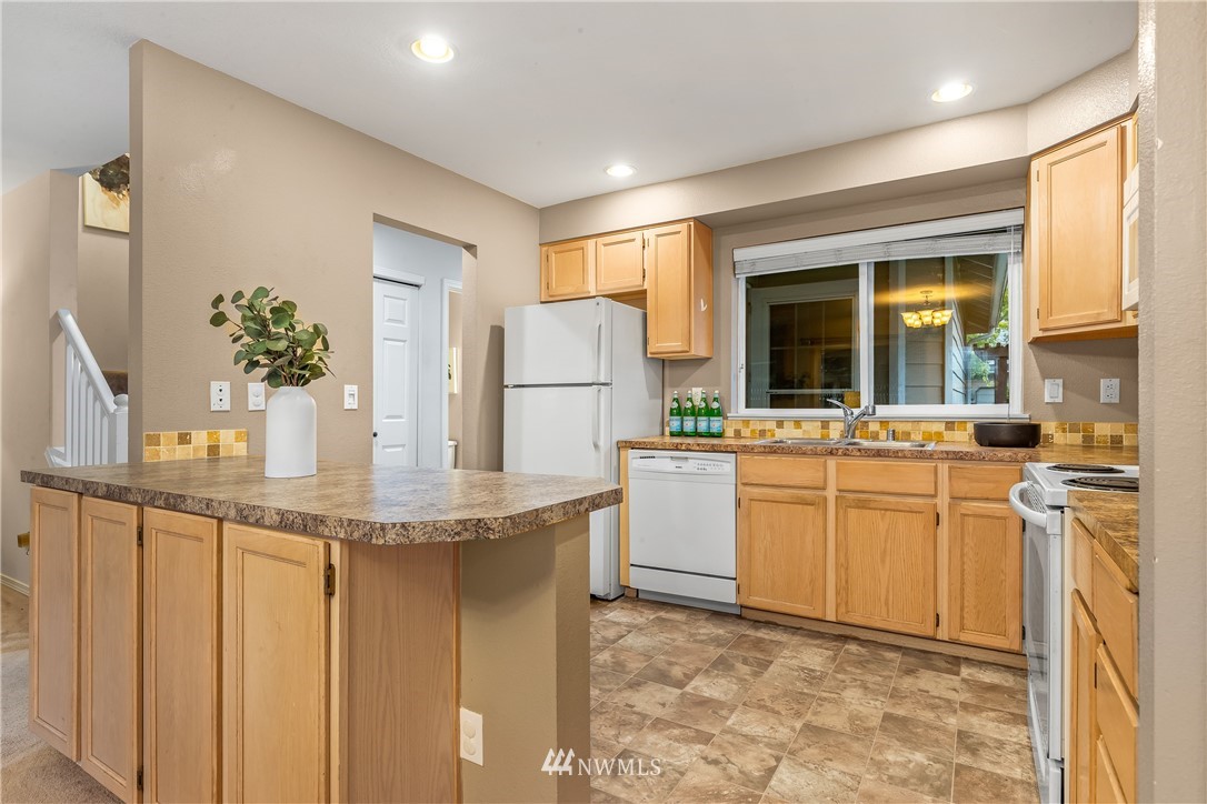 18704 20th Avenue Southeast Bothell, WA 98012 - Photo 6 of 27 a kitchen with stainless steel appliances kitchen island granite countertop a refrigerator a stove and white cabinets with wooden floor