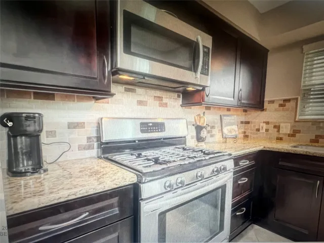 a kitchen with stainless steel appliances granite countertop a sink stove and microwave