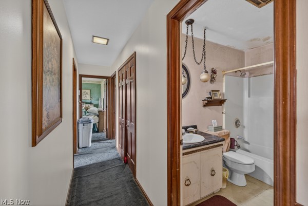 8675 West Smith Road Medina, OH 44256 - Photo 18 of 25 Hallway with wood-finish doors and trim, leading to a bathroom featuring a vanity with a dark countertop and a white tub/shower combination