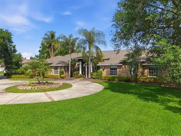 front view of house with a yard and palm trees