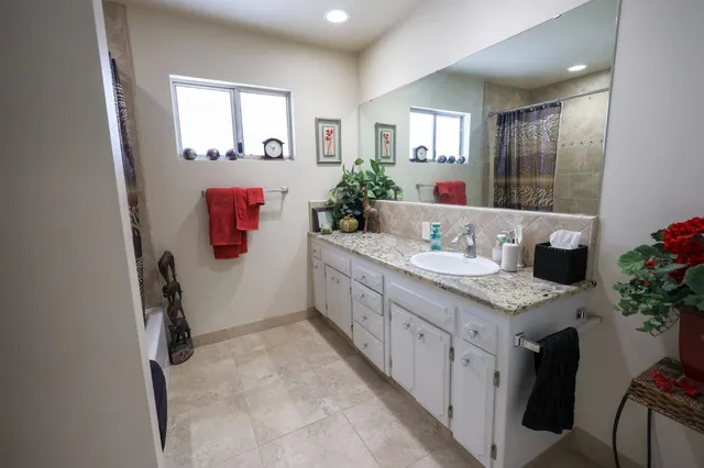 a bathroom with a granite countertop sink a mirror and a shower