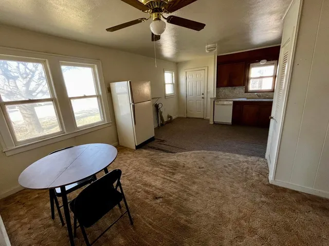 a view of a livingroom with furniture a kitchen and a window