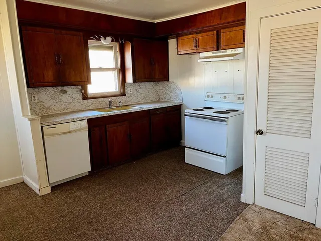 a kitchen with granite countertop a sink stove and cabinets