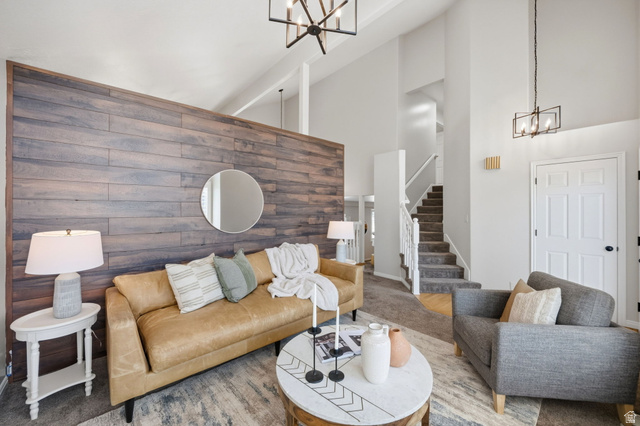 3732 Campbell Road Tooele, UT 84074 - Photo 11 of 69 Vaulted ceiling living room featuring a wood-panel accent wall, contemporary lighting fixtures, light-toned carpeting, and a staircase with white railings