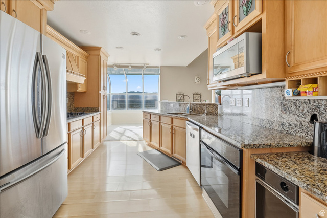2887 View Crest Circle North Logan, UT 84341 - Photo 10 of 37 Kitchen with stainless steel appliances, dark stone countertops, decorative backsplash, and light wood finish cabinetry