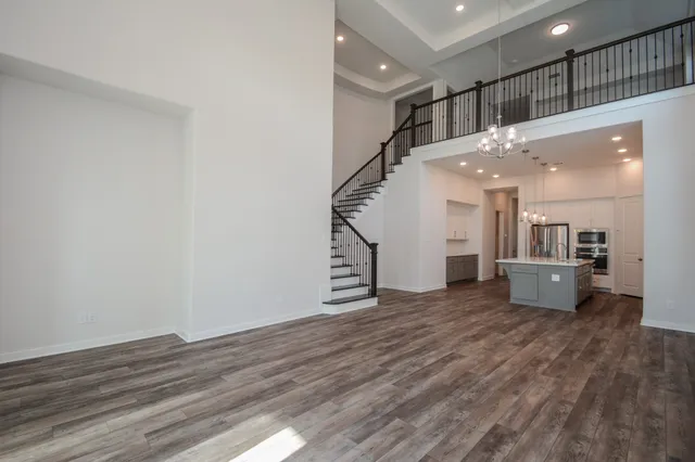 a view of a hallway with wooden floor and a kitchen