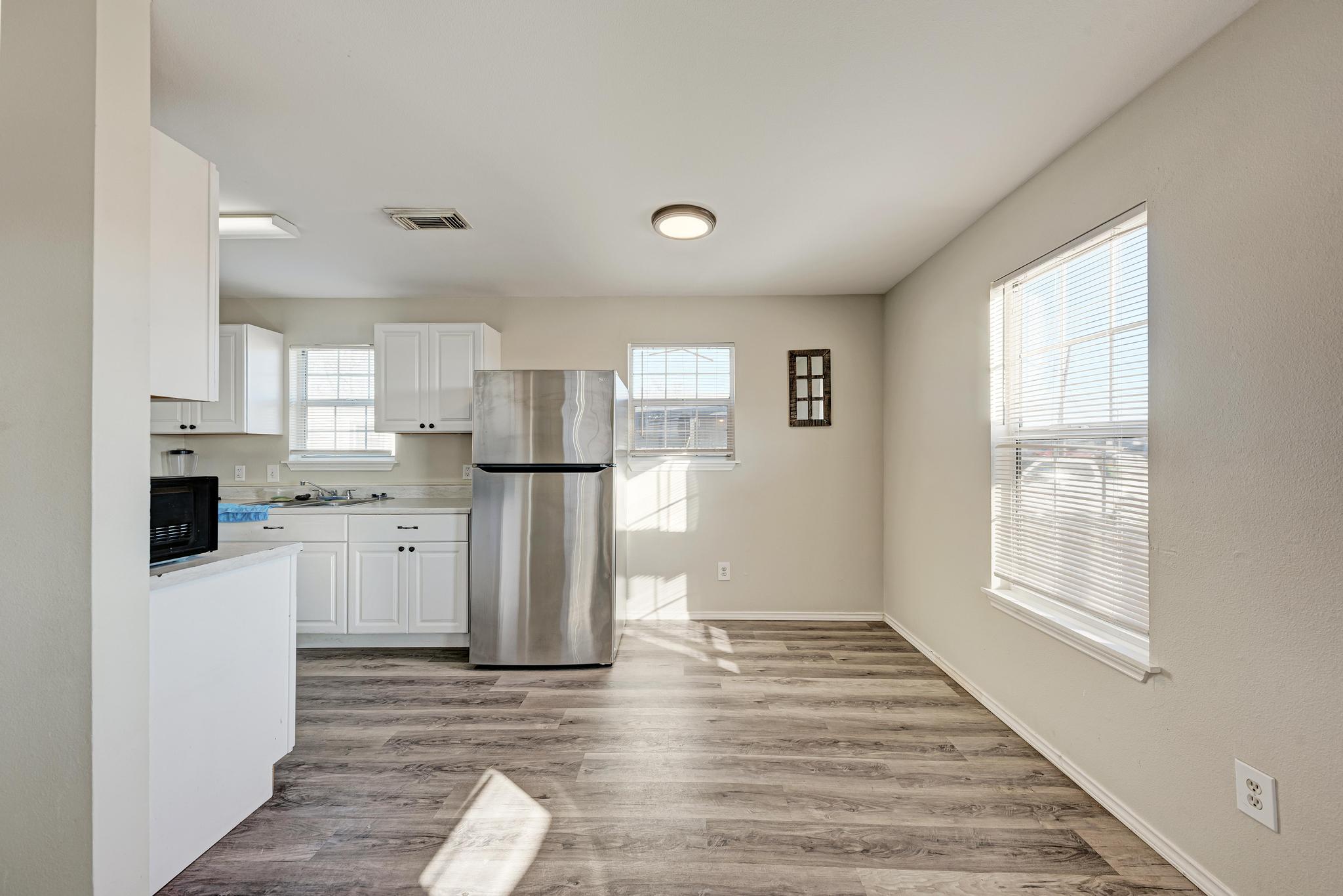 107 West Brenham Street Manor, TX 78653 - Photo 11 of 35 a kitchen with white cabinets and wooden floor