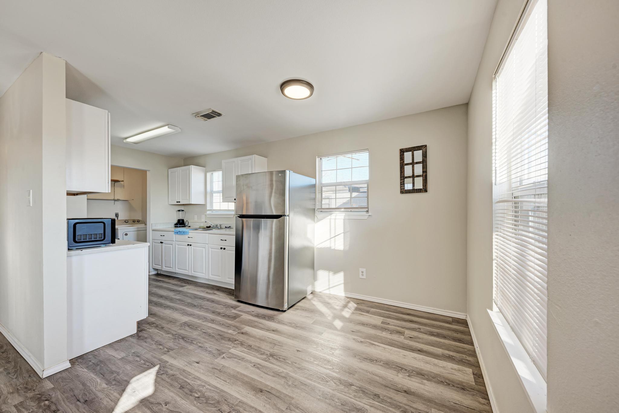 107 West Brenham Street Manor, TX 78653 - Photo 12 of 35 a view of a kitchen with refrigerator and wooden floor