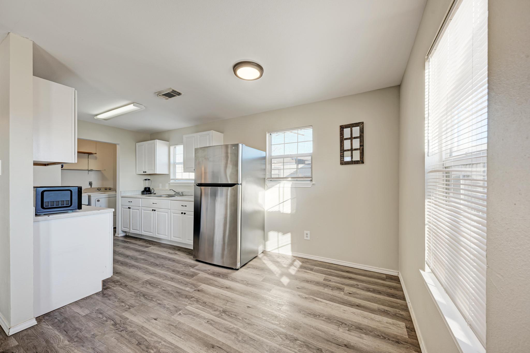 107 West Brenham Street Manor, TX 78653 - Photo 13 of 35 a view of a kitchen with refrigerator and wooden floor
