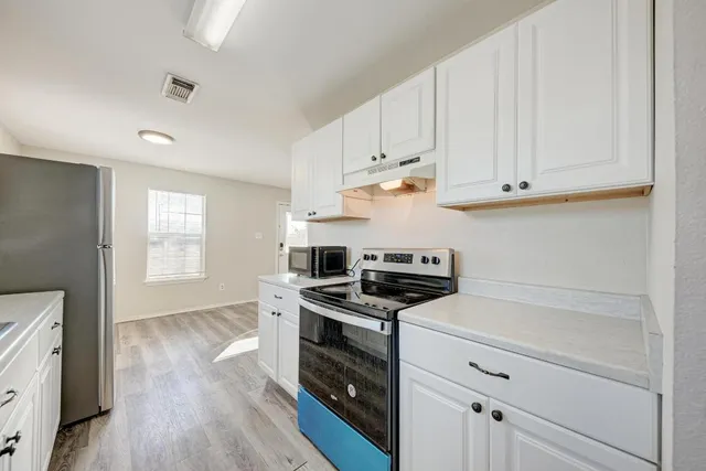 a kitchen with white cabinets and appliances