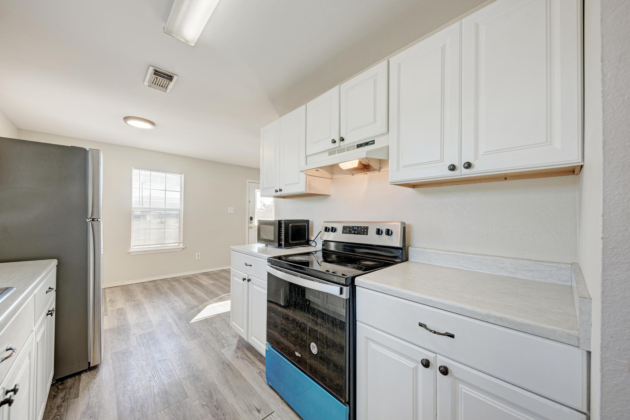 107 West Brenham Street Manor, TX 78653 - Photo 18 of 35 a kitchen with white cabinets and appliances