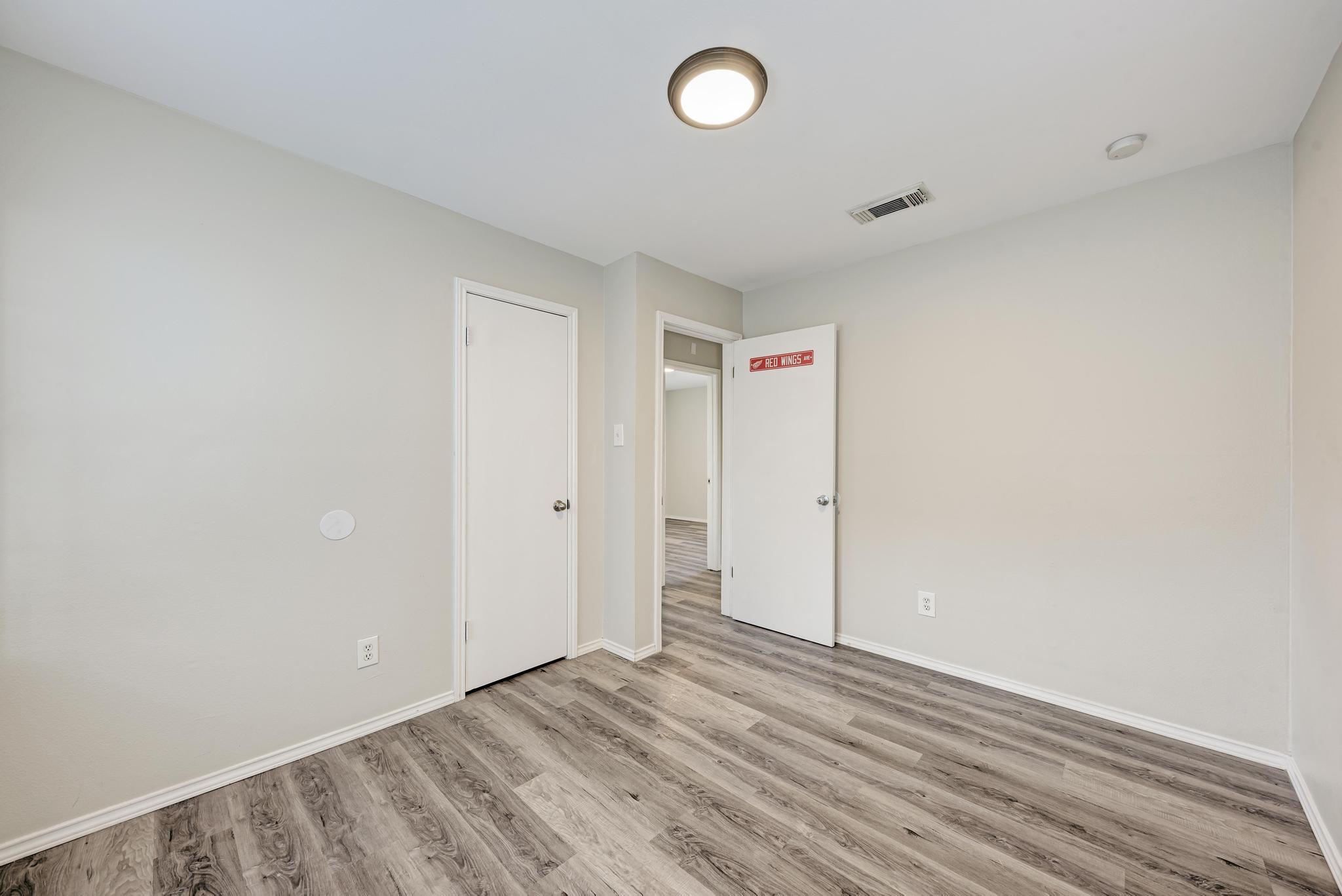 107 West Brenham Street Manor, TX 78653 - Photo 28 of 35 an empty room with wooden floor and windows