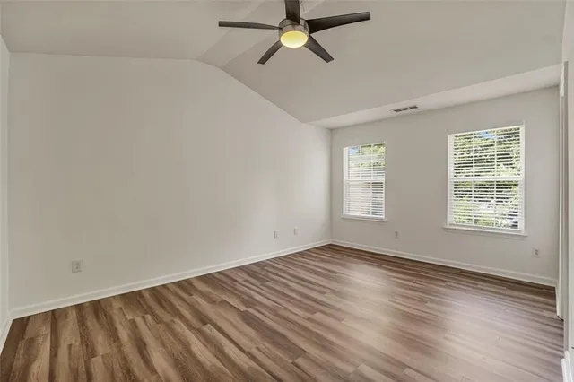a view of an empty room with wooden floor and window