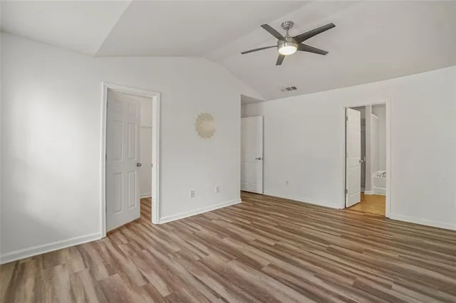 an empty room with wooden floor and ceiling fan