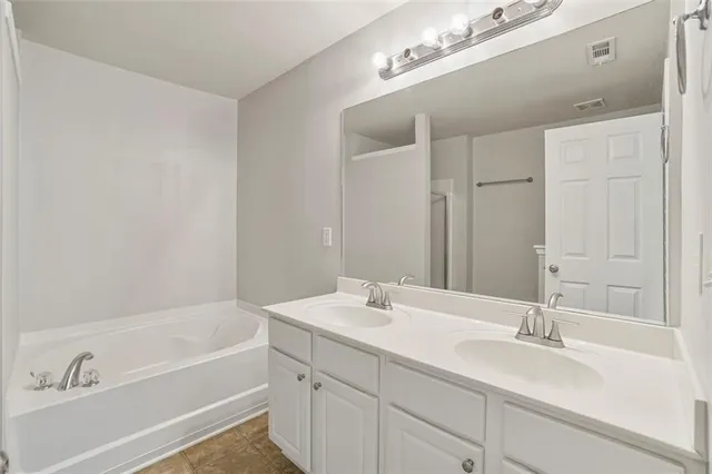a bathroom with a tub a sink and mirror
