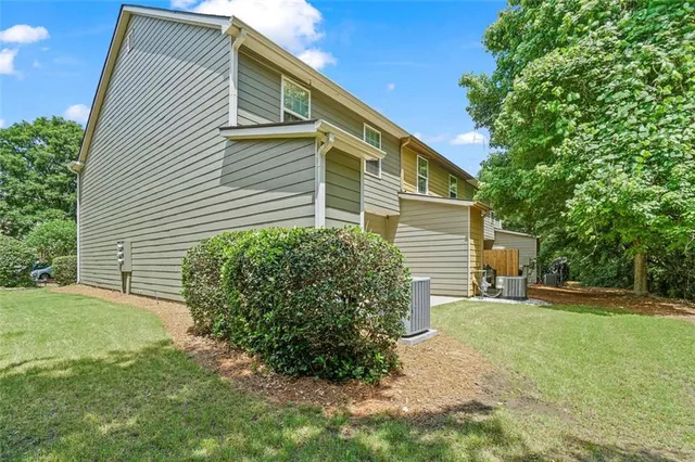 a backyard of a house with plants and large tree