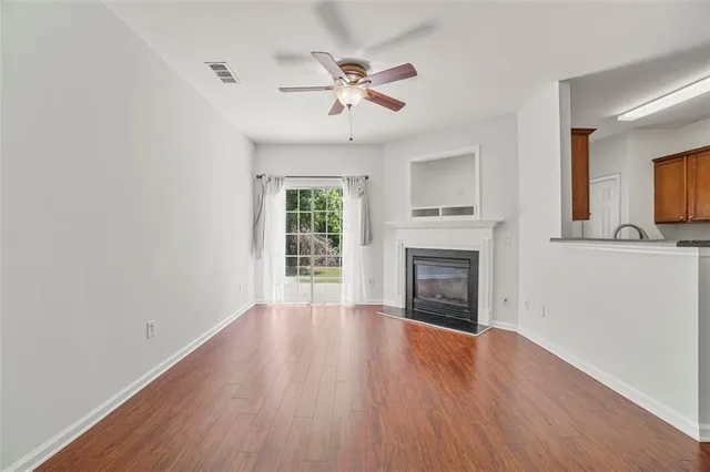 an empty room with wooden floor fireplace and windows