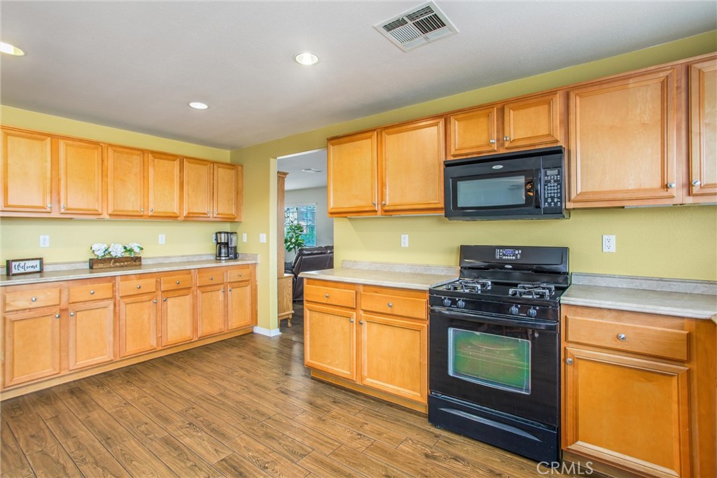 4423 Candelaria Way Perris, CA 92571 - Photo 13 of 42 a kitchen with stainless steel appliances granite countertop wooden cabinets a stove a sink and a window