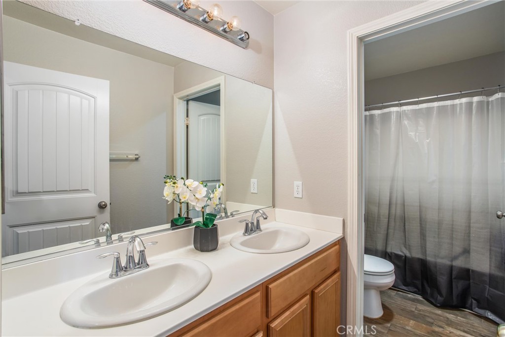 4423 Candelaria Way Perris, CA 92571 - Photo 28 of 42 a bathroom with a granite countertop sink toilet a large mirror and shower