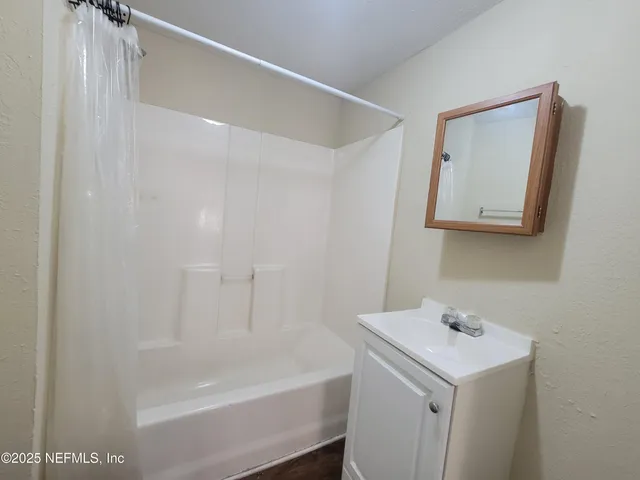 a white bath tub sitting next to a white sink and vanity