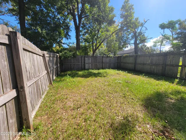 a view of backyard with wooden fence and trees