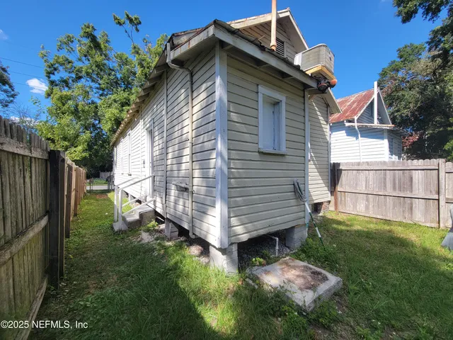 a view of backyard with wooden fence and large trees