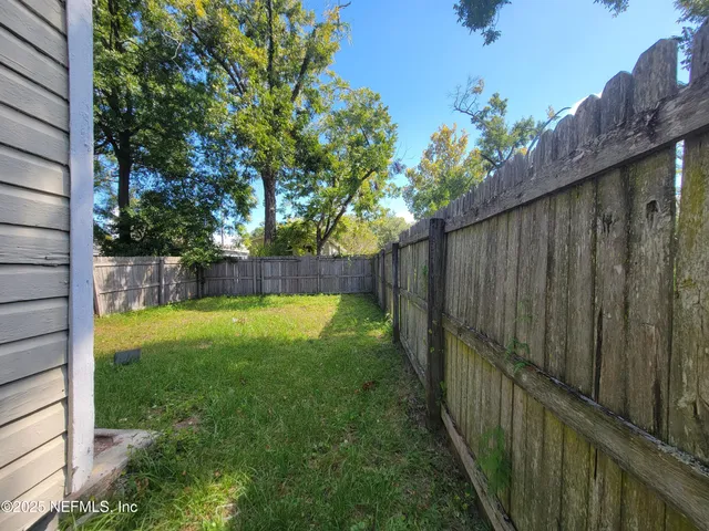 a view of backyard with wooden fence and large trees