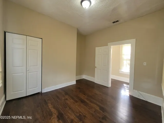 an empty room with wooden floor & windows