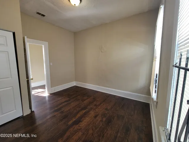 an empty room with wooden floor and entrance