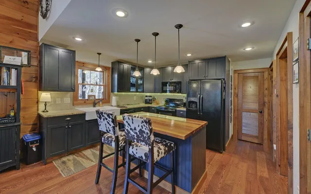 a view of a dining room and livingroom with furniture wooden floor a rug a fireplace and a chandelier