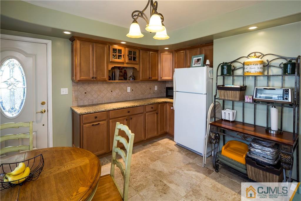 122 Ridge Road Colonia, NJ 07067 - Photo 12 of 25 a kitchen with stainless steel appliances granite countertop a stove a refrigerator and a dining table with wooden floor