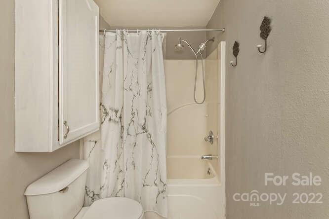 1411 Bailey Branch Road Burnsville, NC 28714 - Photo 19 of 40 a bathroom with a shower curtain and a toilet