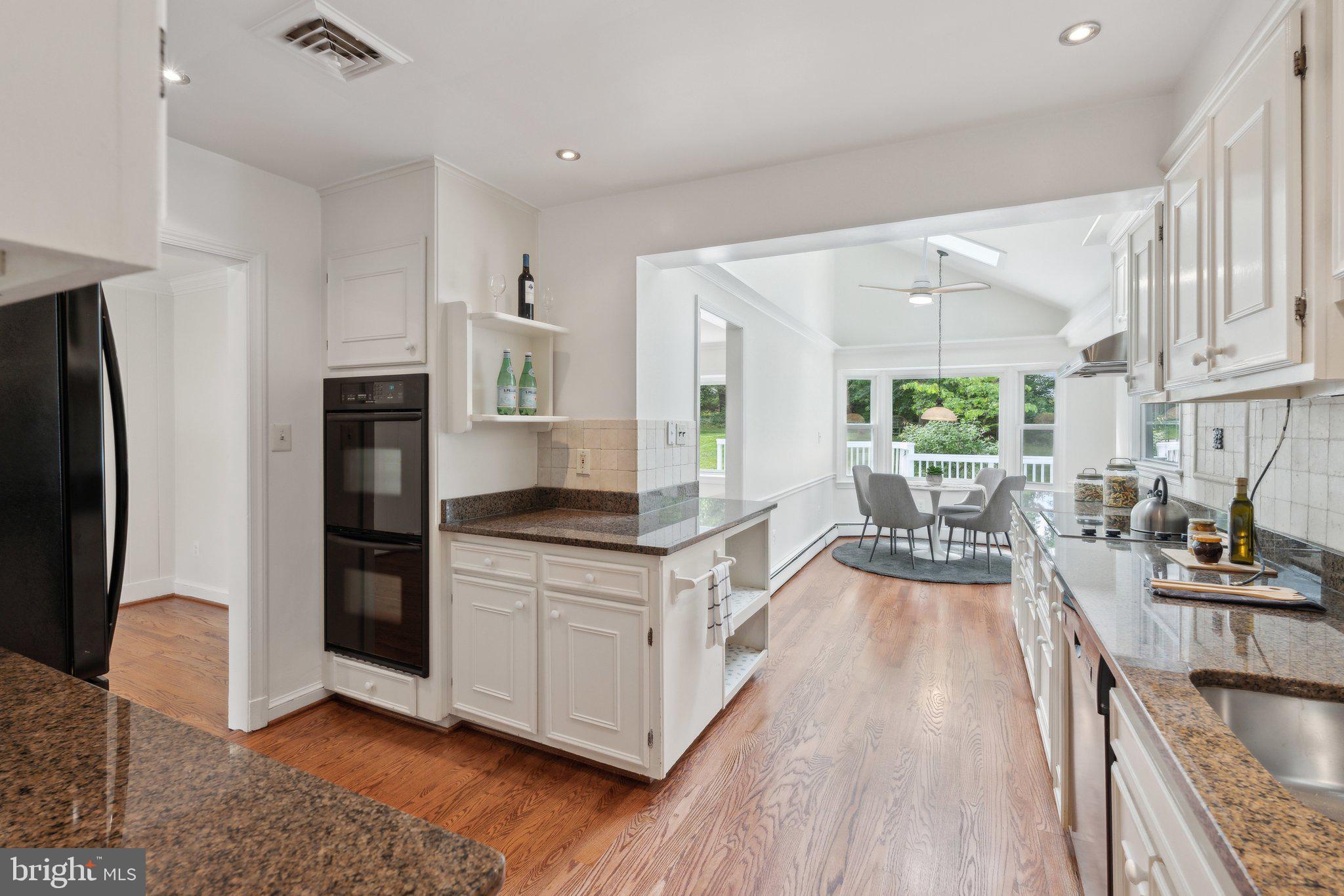 701 Notley Road Silver Spring, MD 20904 - Photo 20 of 60 a kitchen with stainless steel appliances granite countertop a stove a refrigerator a sink a dining table and chairs with wooden floor