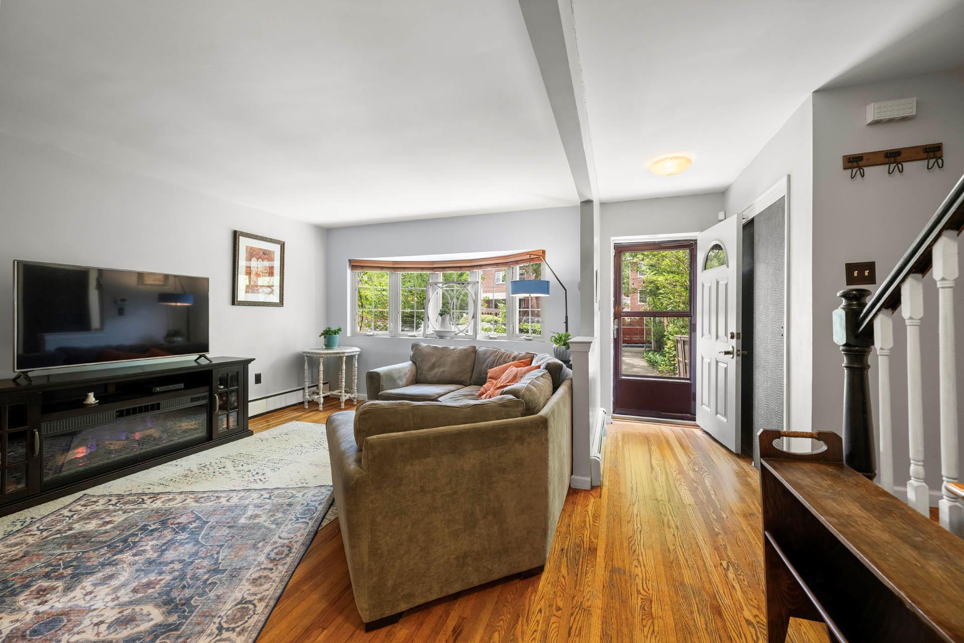 5922 Post Road Bronx, NY 10471 - Photo 8 of 13 Living area featuring a baseboard heating unit, wood finished floors, stairs, beam ceiling, and baseboards