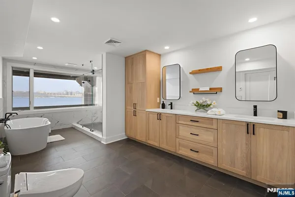 a spacious bathroom with a double vanity sink a mirror and a bathtub