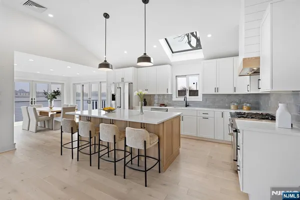 a kitchen with stainless steel appliances kitchen island granite countertop a sink a stove a dining table chairs and view kitchen