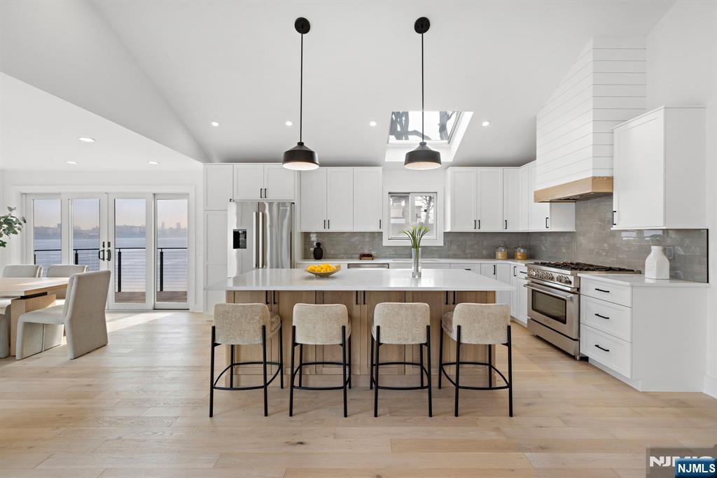 27 Shore Road Edgewater, NJ 07020 - Photo 5 of 48 a open kitchen with stainless steel appliances granite countertop a stove a sink a oven a dining table and chairs with wooden floor