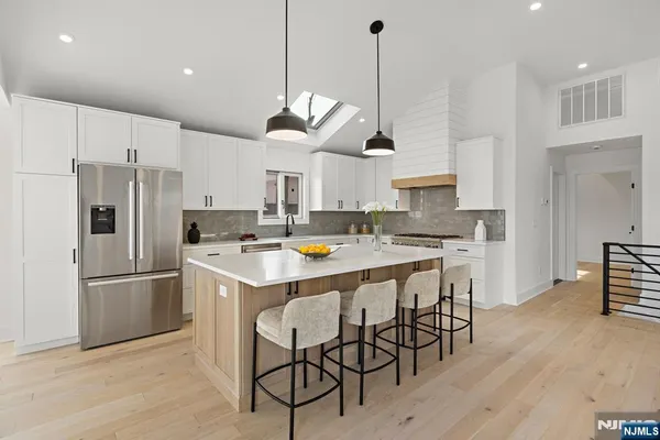 a kitchen with stainless steel appliances kitchen island a refrigerator a stove and white cabinets
