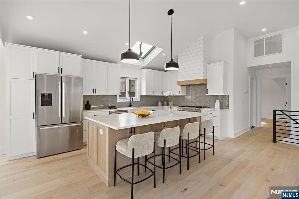 27 Shore Road Edgewater, NJ 07020 - Photo 6 of 48 a kitchen with stainless steel appliances kitchen island a refrigerator a stove and white cabinets