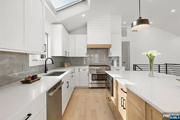 a kitchen with a stove a sink a refrigerator and chairs