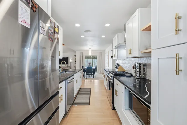 a kitchen with stainless steel appliances granite countertop lots of counter space and a refrigerator