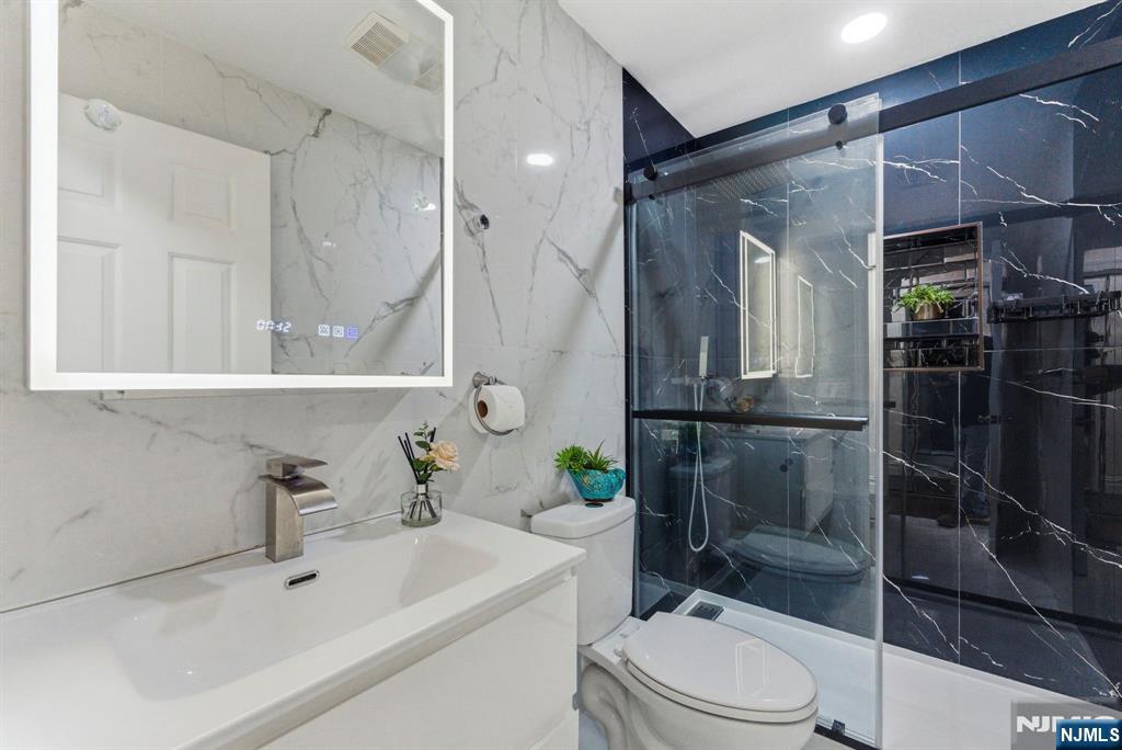 144 70th Street, Unit 1E Guttenberg, NJ 07093 - Photo 8 of 20 a bathroom with a sink toilet and shower