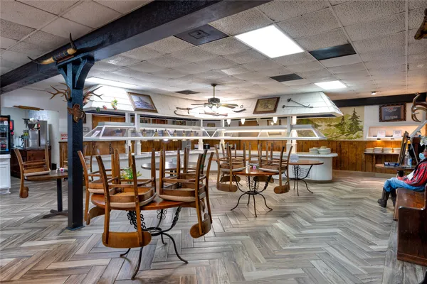 a dining room with stainless steel appliances kitchen island a table chairs and a bookshelf