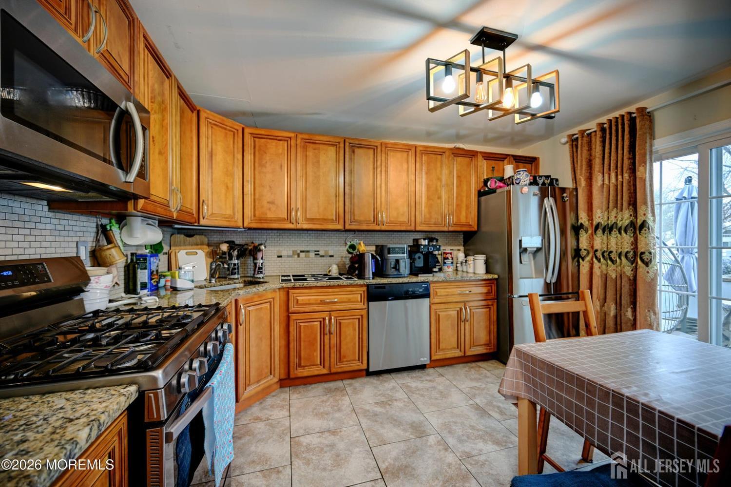 22 Borell Square Parlin, NJ 08859 - Photo 10 of 32 a kitchen with stainless steel appliances granite countertop a stove top oven a sink dishwasher a dining table and chairs with wooden floor
