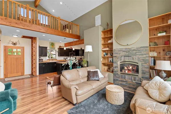 a living room with furniture a fireplace a rug and a kitchen