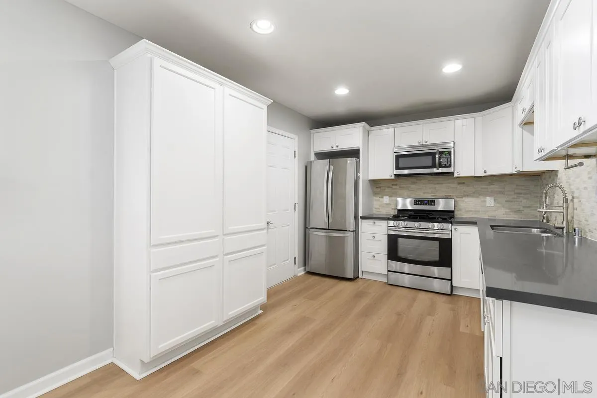 180 5th Avenue Chula Vista, CA 91910 - Photo 6 of 18 a kitchen with kitchen island a white cabinets and refrigerator