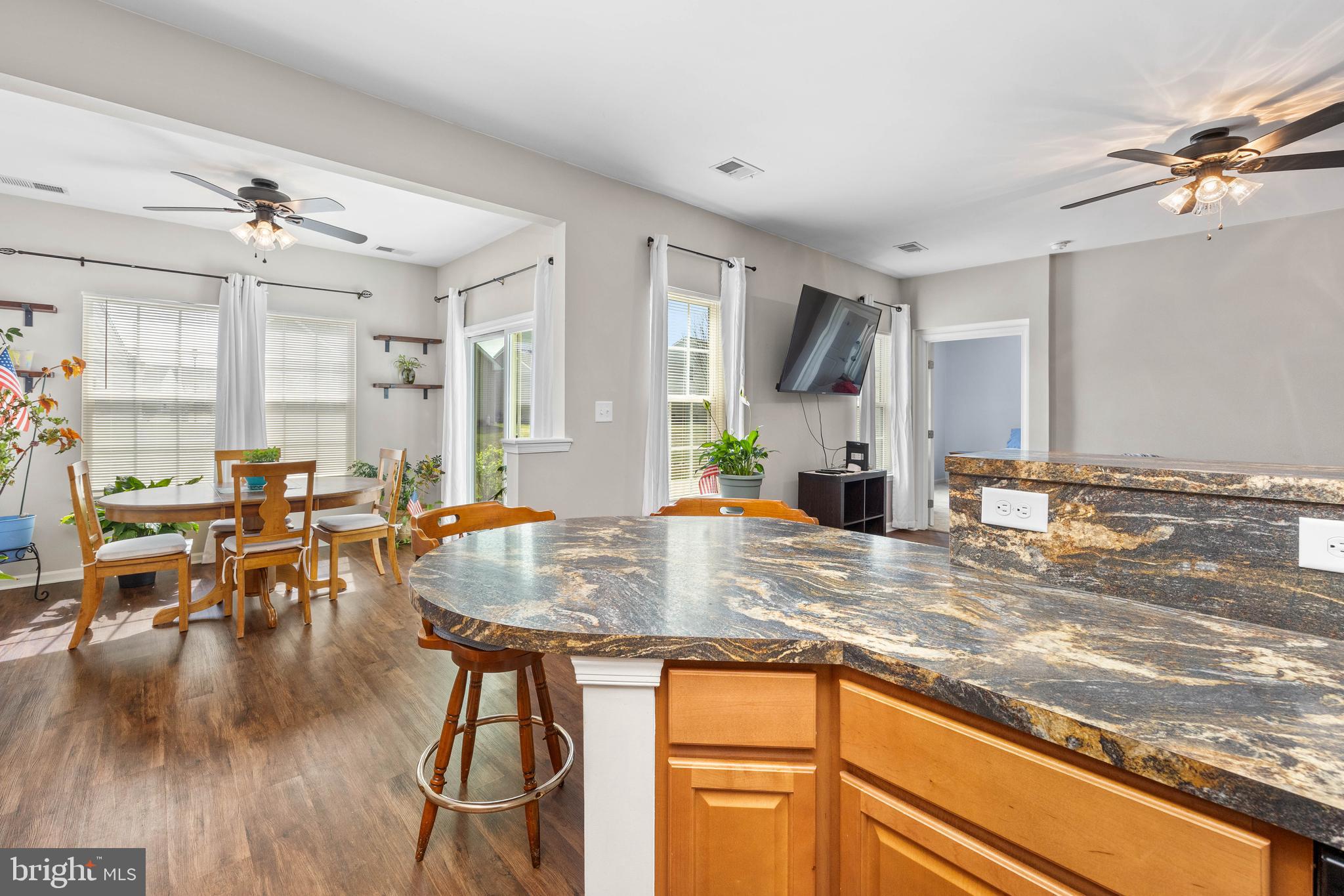 191 Bobbys Branch Road Millsboro, DE 19966 - Photo 11 of 40 a kitchen with stainless steel appliances granite countertop a stove top oven a sink a dining table and chairs with wooden floor