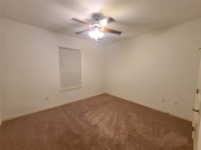 an empty room with a chandelier fan and windows